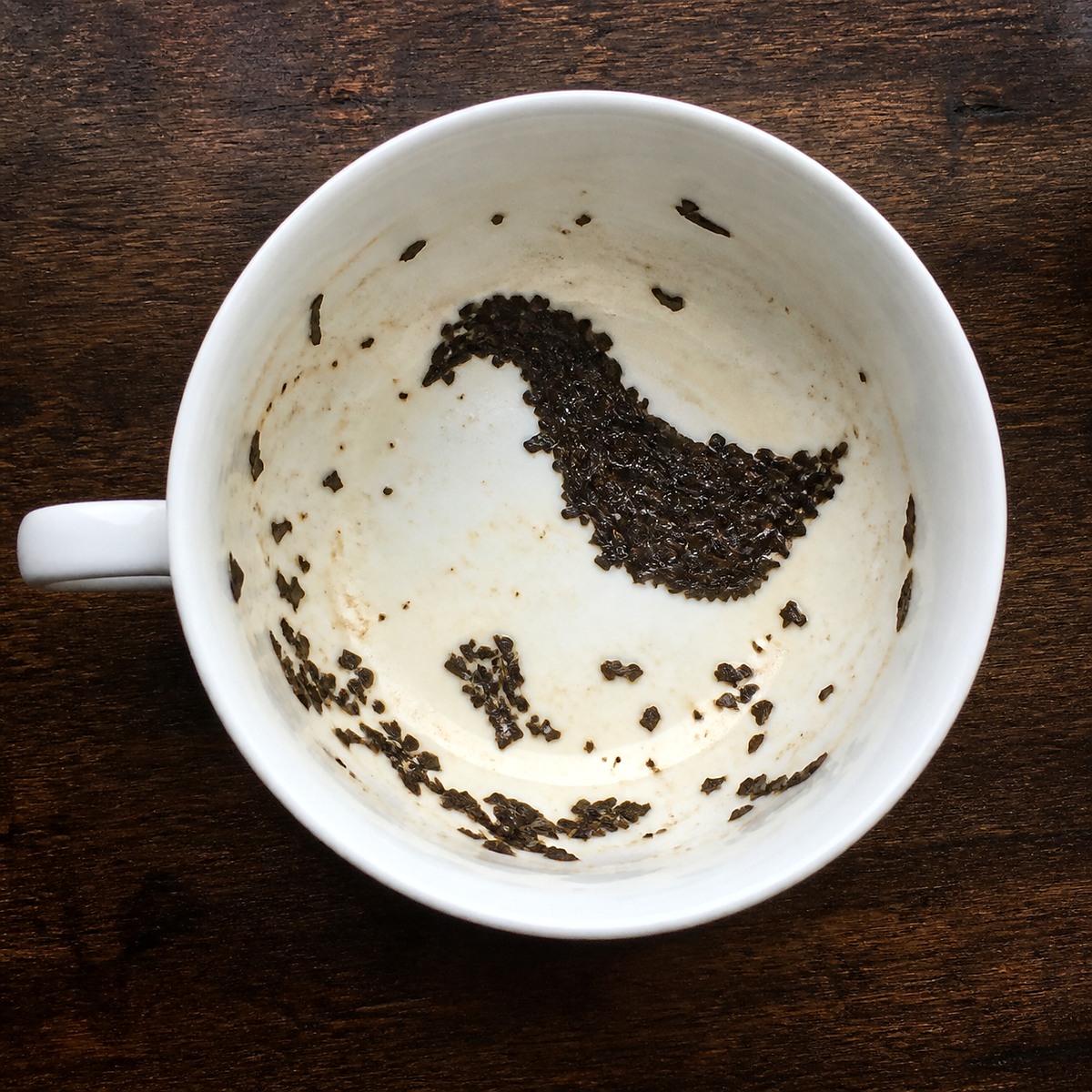 Emptied teacup with tea leaves forming a symbolic shape